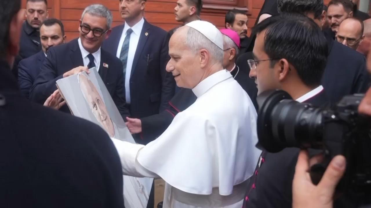 Pope Leo XIV receives a painting as he leaves the Patriarchal Church of Saint George in Istanbul