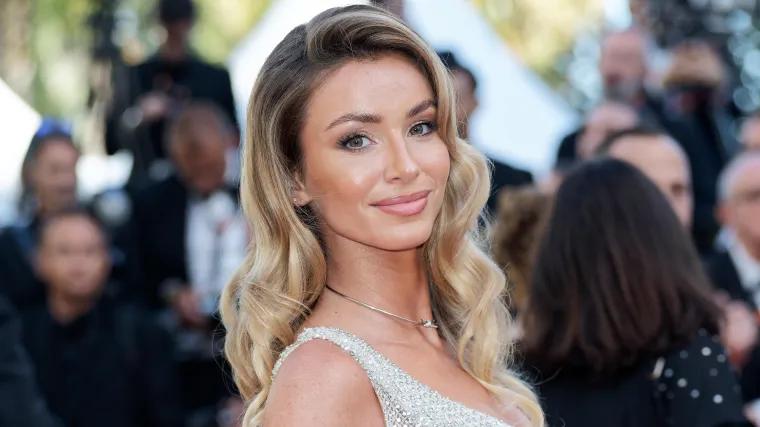 Flawless WAG stuns in glittering mini-dress, high heels lounging on bed