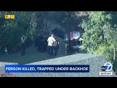 Person dies after being trapped under backhoe in backyard of home