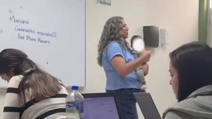 Maestra carga a bebé de su alumna para que termine sus actividades en clase