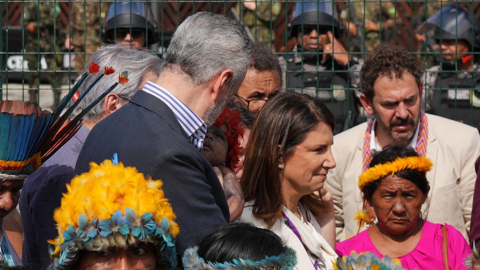 UN climate talks president holds baby during Indigenous people's protest blocking entry to venue
