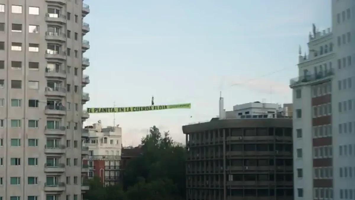 Una activista camina por una cuerda floja a 30 metros de altura en la Plaza de España de Madrid