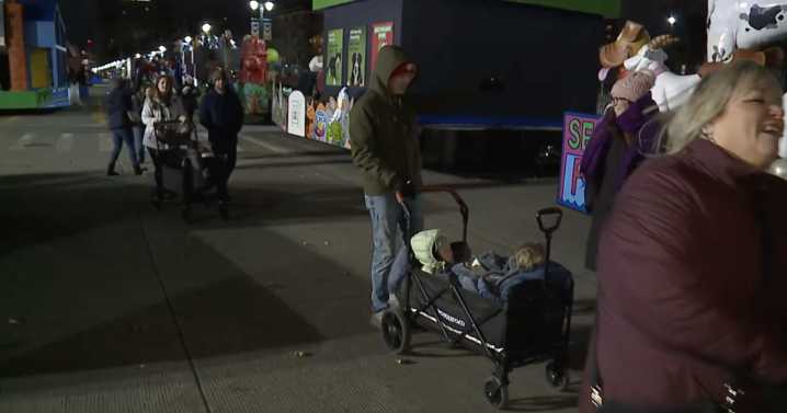 Families walk Woodward the night before Thanksgiving parade in winds conditions