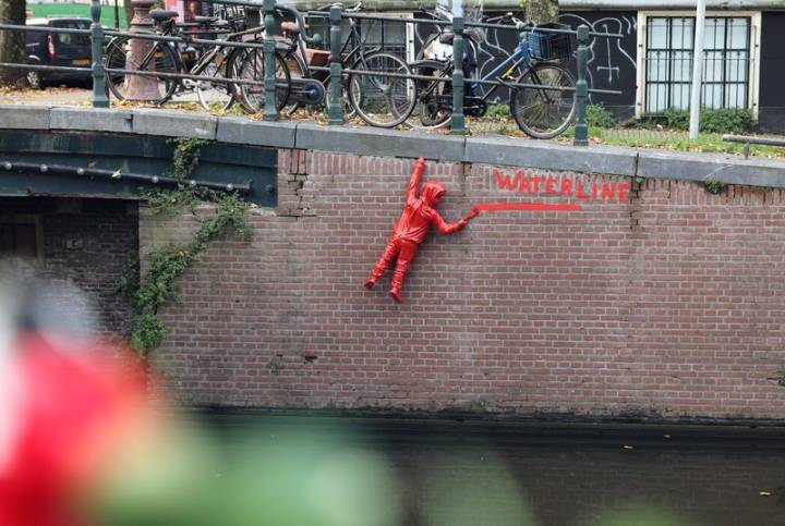French artist's striking red figures in Amsterdam canals protest climate crisis