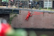 French artist's striking red figures in Amsterdam canals protest climate crisis