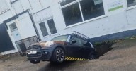 Mini in danger of being 'eaten' by giant freak sinkhole in bakery car park