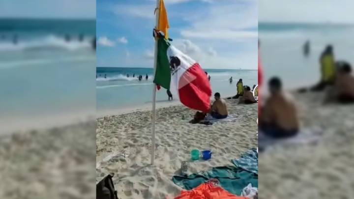 Guardavidas retiran bandera mexicana colocada en asta bandera de emergencia en Cancún