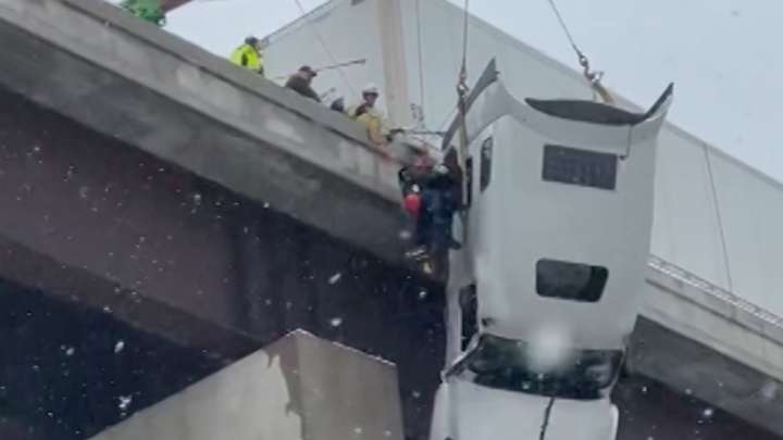 Driver rescued from tractor-trailer dangling over bridge