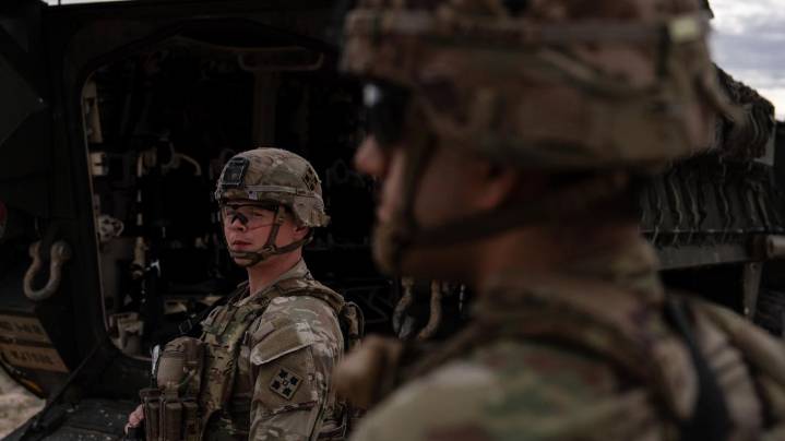 A man is halted climbing the US-Mexico border wall. Under new Trump rules, US troops sound the alarm
