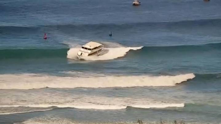 Yacht-sized passenger boat runs aground in high surf off Hawaii beach