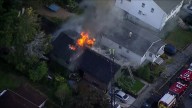 Flames shoot from roof as crews battle house fire in Medford