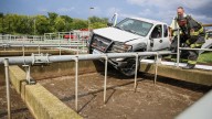 Pickup truck left dangling over wastewater tank after suburban crash, officials say