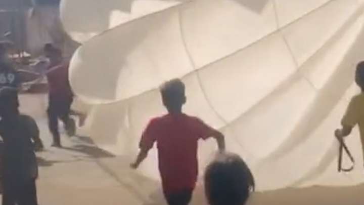 Children in Gaza play games with aid drop parachute