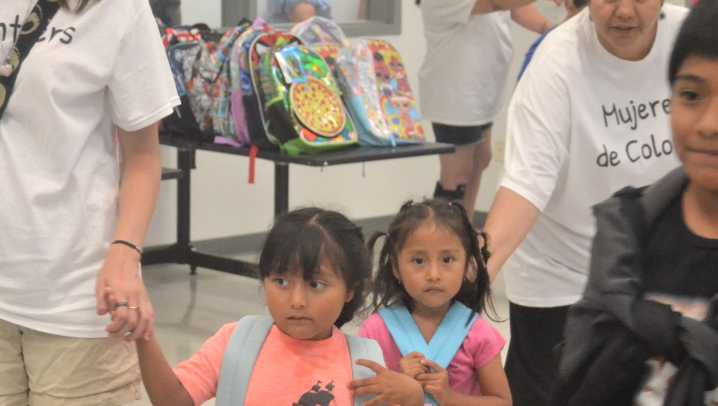 Mujeres de Colores distributing school backpacks at Aug. 9 block party