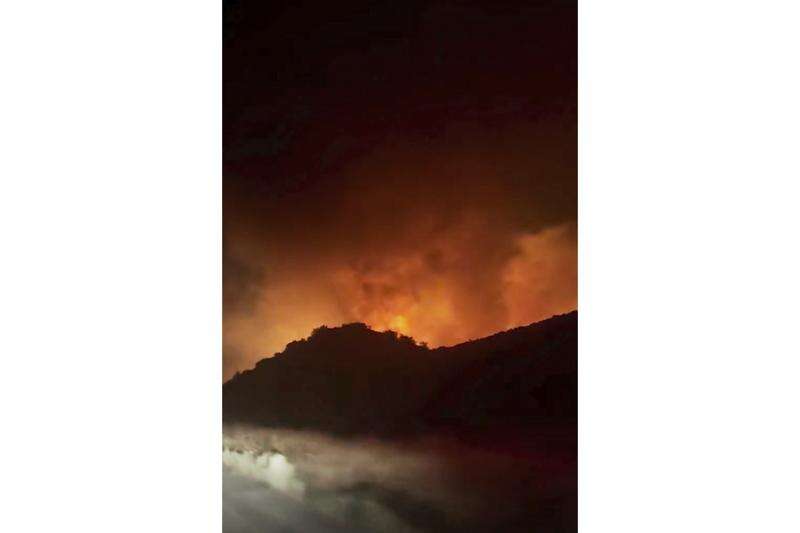 Firefighters battle a fast-moving blaze along a highway north of Los Angeles