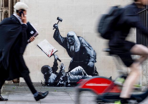 Banksy unveils a new mural of a judge beating a protester outside London court