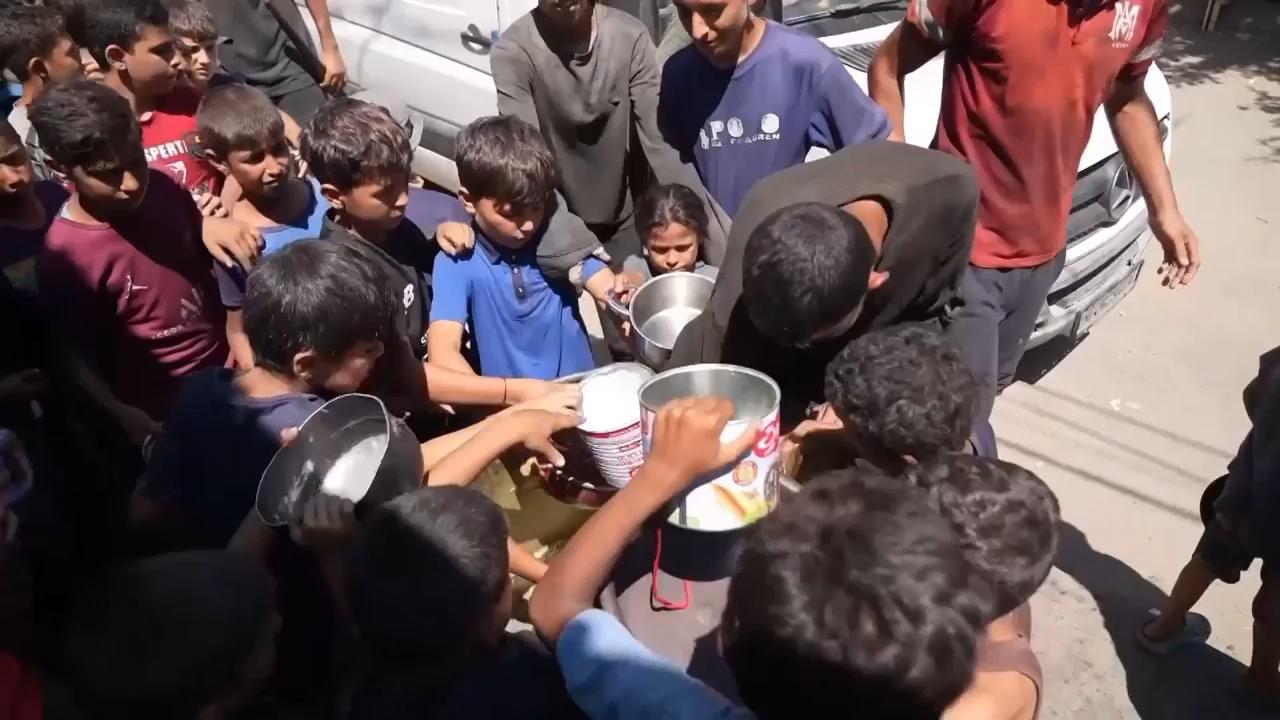 Palestinians displaced from Gaza City join queues for food at charity kitchen in Deir al