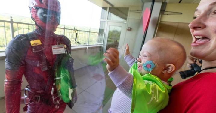 Superheroes show up to clean windows and bring smiles to the American Family Children's Hospital