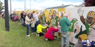 Green and gold faithful paint fence near Lambeau Field ahead of season opener