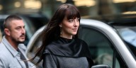 Dakota Johnson Wears Black Cape Minidress and Knee-High Vinyl Boots in Zurich