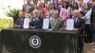 Gov. Greg Abbott signs camp safety bills into law, surrounded by Camp Mystic families