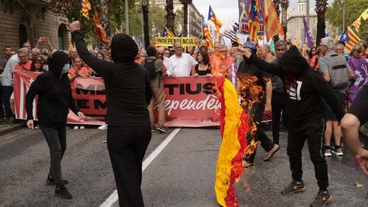 Cinco manifestantes encapuchados queman una bandera de España frente a la manifestación independentista de Barcelona