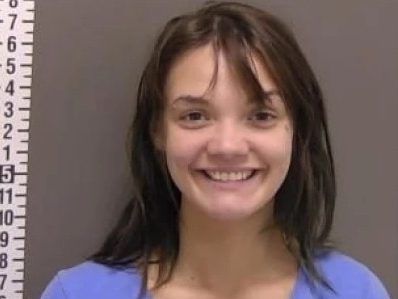 Woman grins for mugshot after hitting boyfriend with hatchet