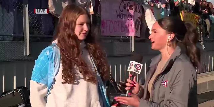 Audrey talks with football fan at Waunakee High School