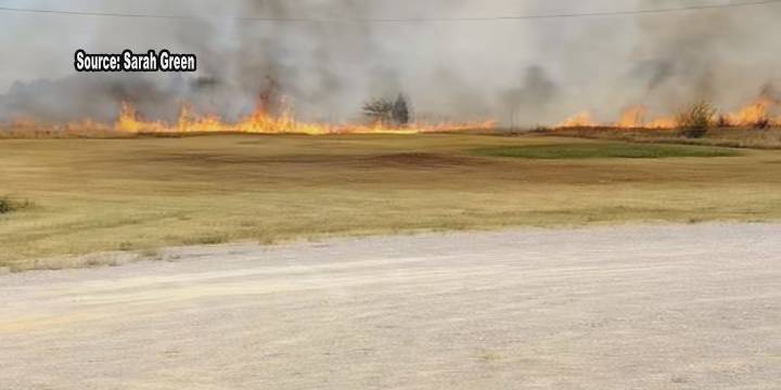 Business owner reacts after brush fire spreads close to building