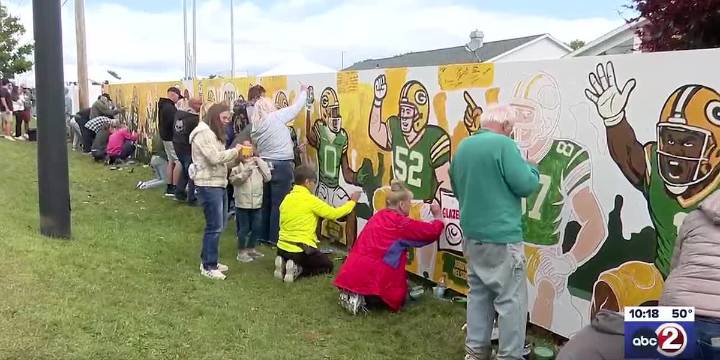 Green and gold faithful paint fence near Lambeau Field ahead of season opener