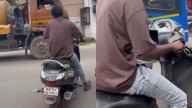 Man seen riding two-wheeler with phone in one hand, laptop on lap amidst heavy traffic, video sparks outrage