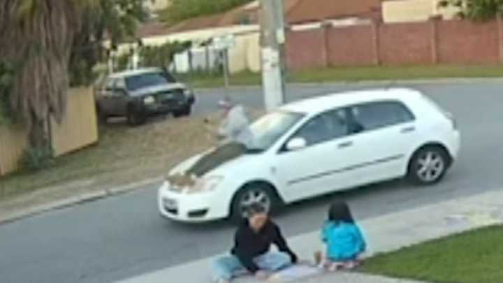 A driver has been caught on camera flying through a suburban Perth street with a passenger riding on the car bonnet.