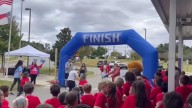 3rd graders cheer on classmate as she crosses fun run finish line using her walker