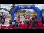 3rd graders cheer on classmate as she crosses fun run finish line using her walker