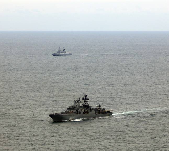Navy destroyer and helicopter shadows Russian warship sailing through UK waters