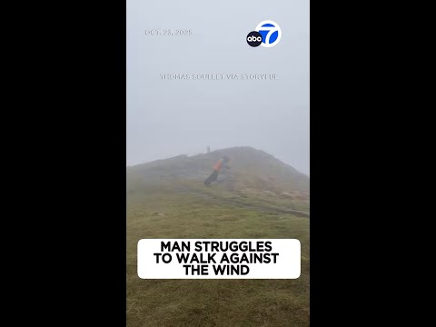 Man struggles to walk against powerful winds